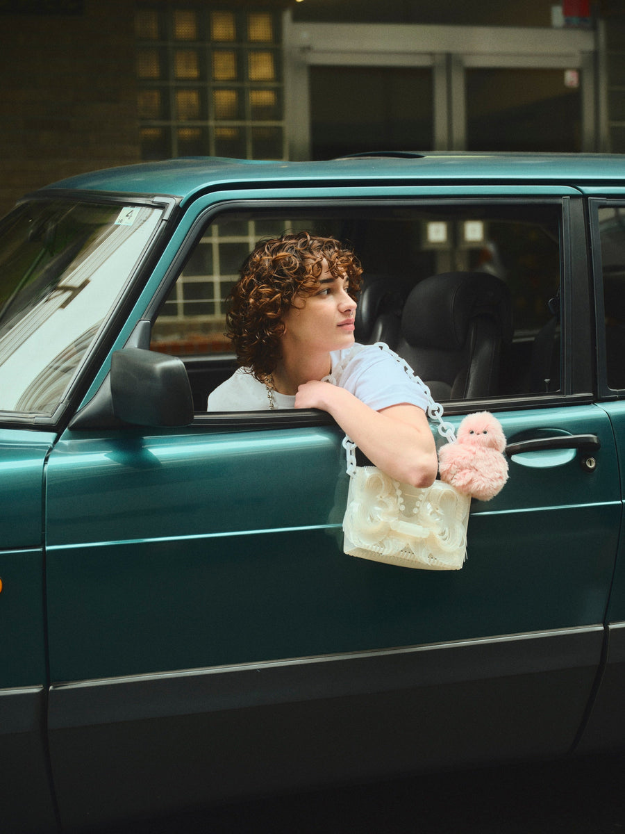 Person leaning out of a car window with a pink Mirumi attached to their bag